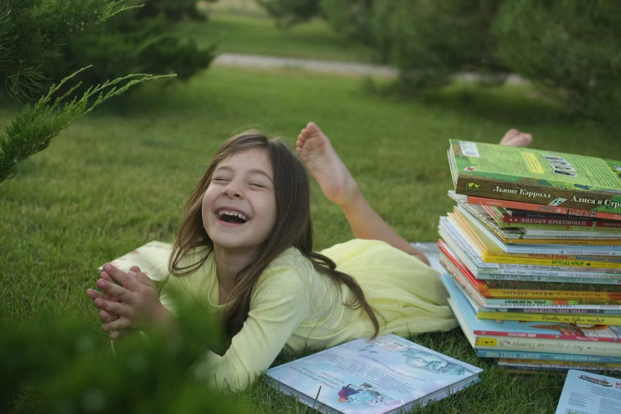 Девочка с любимыми книгами на траве